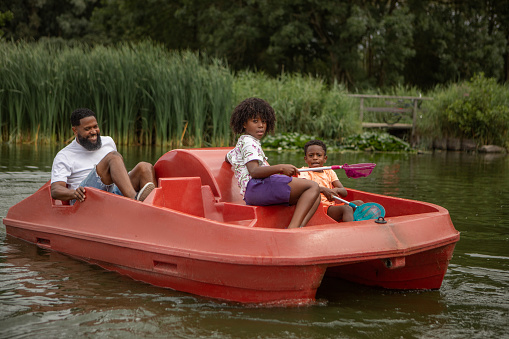 Black Father and two Sons having fun on a water bike on the water