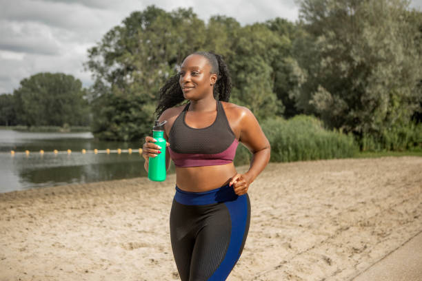 istock Black woman working out by the beach and water 1557782346