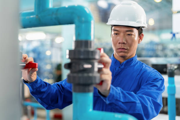 istock Engineer with expertise in the industry is seen meticulously examining the water pipeline before it enters the advanced filtration machine at mineral factory for recycling process. Essence of the food and drink industry. 1557794884