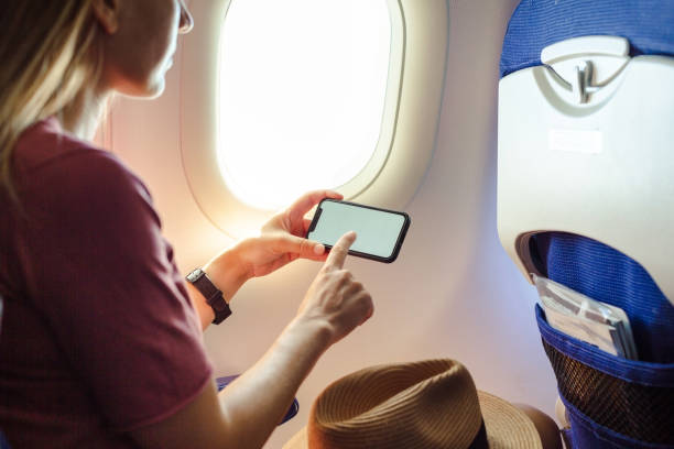 istock Young woman using smart phone in passenger airplane 1557797001