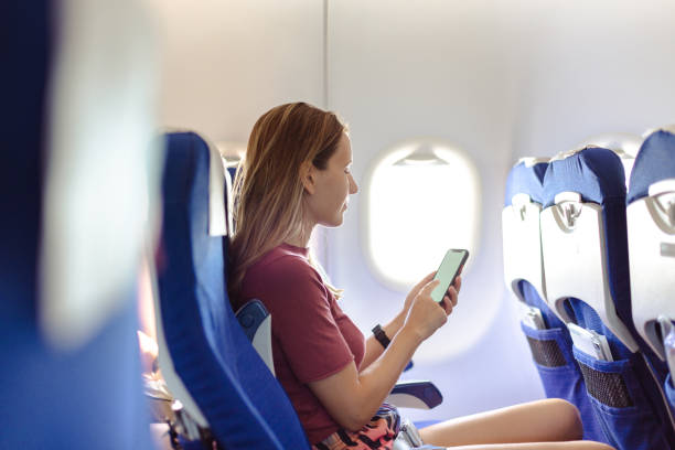 istock Woman in the airplane holding smart phone with white screen 1557797004