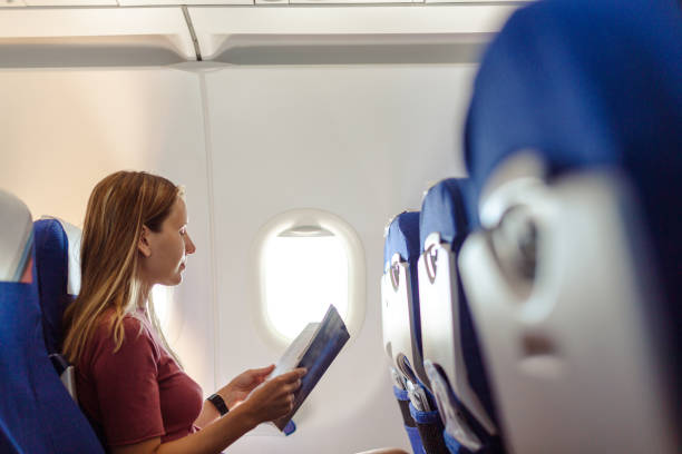 istock Woman traveling by plane and reading a magazine 1557798577