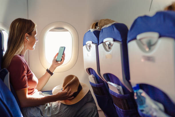 frau im flugzeug, die smartphone mit weißem bildschirm hält - economy class stock-fotos und bilder