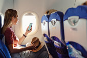 Woman in the aircraft holding smart phone with white screen