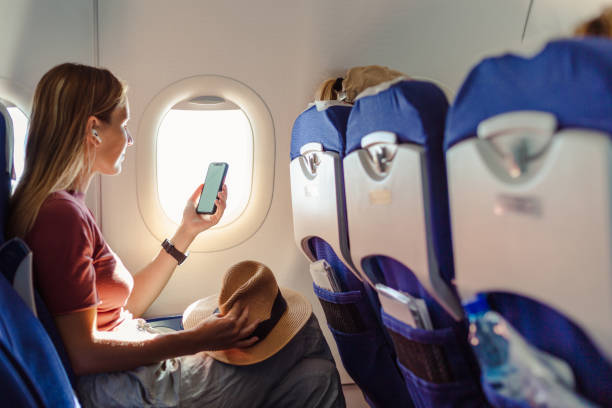 Woman in the aircraft holding smart phone with white screen stock photo
