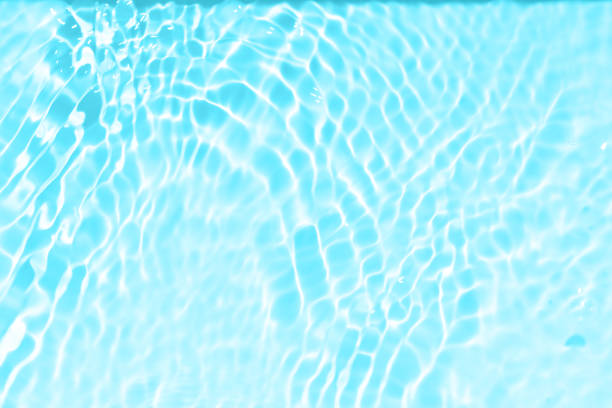 istock Blue water with ripples on the surface. Defocus blurred transparent blue colored clear calm water surface texture with splashes and bubbles. Water waves with shining pattern texture background. 1557807359