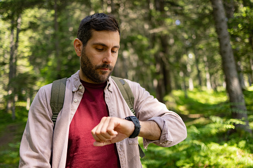 Young male tourist checking his steps on a watch during springtime in nature.