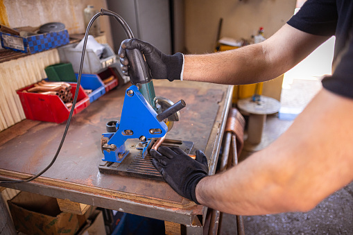 Worker grinding metal components with determination in his shop.