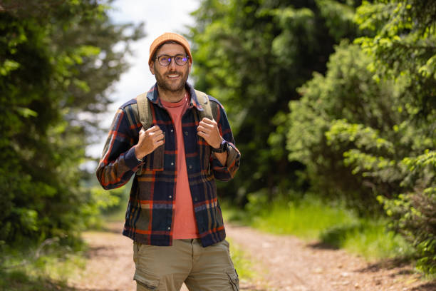 istock Happy male backpacker enjoying while standing in nature. 1557815798