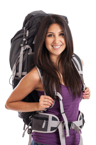 A beautiful mixed race young woman wearing a large travel backpack isolated on white