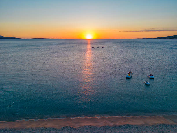 Pastel sunrise over the Mediterranean sea. Drone point of view with three boats anchored.