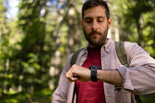 Male tourist checking his steps on a watch during springtime in nature. Focus is on arm.