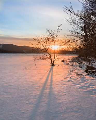 Winter landscape. Sunset over a frozen lake that is covered in snow.