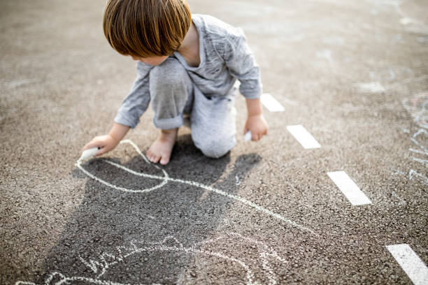 istock Young boy doodling the asphalt with a chalk 1557862498