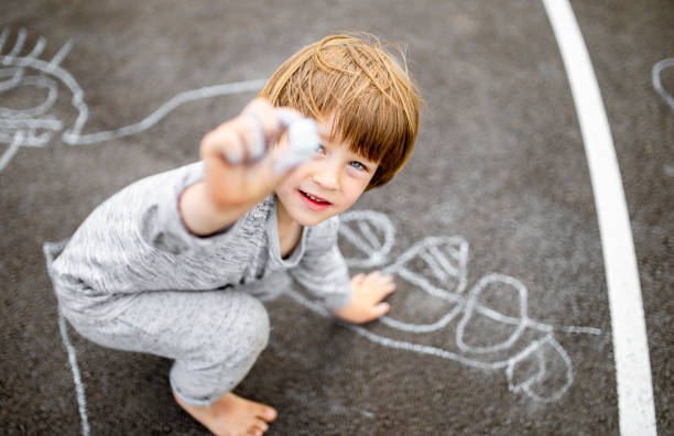 istock Young boy doodling the asphalt with a chalk 1557862499