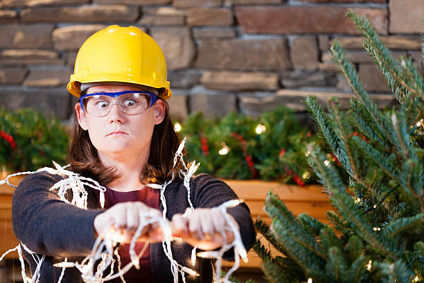 A woman plugging in her Christmas tree lights stock photo