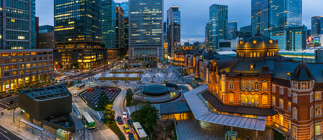 High angle view over the busy Marunouchi plaza at dusk, overlooked by the crowded skyscraper cityscape of central Tokyo, Japan’s vibrant capital city.