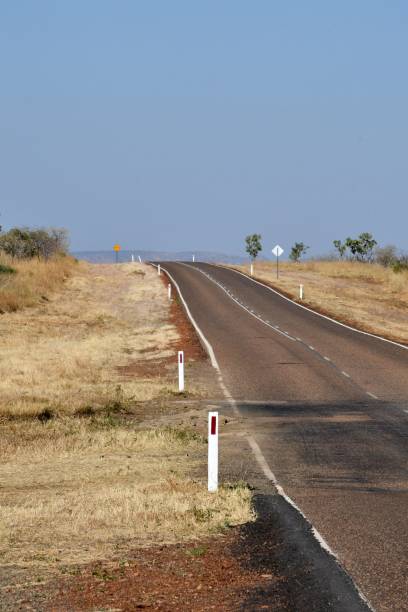 istock Road signs and markers beside a road bordered by dry grass. 1557881163