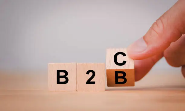 Photo of Supply change between Business supplier and customer relations concept with Hand flipping wooden cubes block for change wording B2B to B2C.