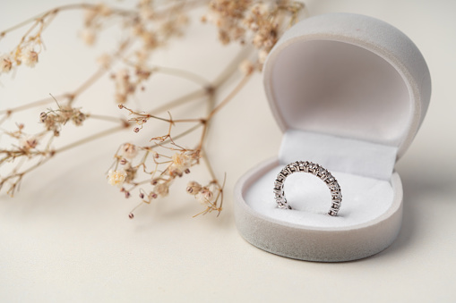 Golden diamond ring in the box with white flower background close up