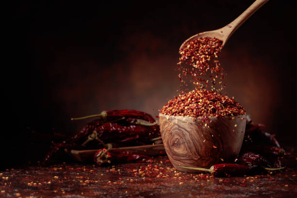 istock Chilli flakes are poured into a wooden dish. 1557935351