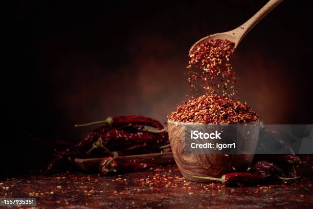 Chilli Flakes Are Poured Into A Wooden Dish Stock Photo - Download Image Now - Herbal Medicine, Herb, Chili Pepper