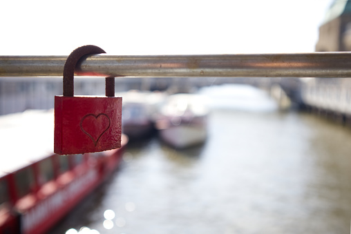 Red lock with a heart on a fence grate with an empty space as a symbol of love