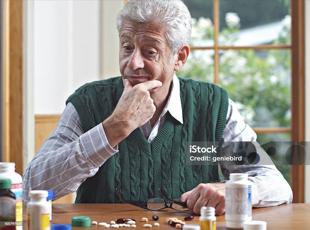Pensive homme senior donne à ses nombreux détails - Photo de Complément vitaminé libre de droits