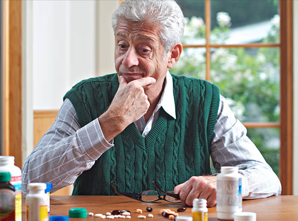 istock Thoughtful senior man looks at his many pills 155797437