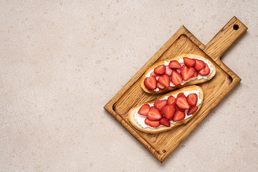 Strawberry and cream cheese sandwich on cutting wooden board, top view with copy space