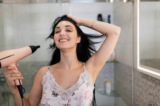 Immerse yourself in this young woman's soothing beauty ritual as she indulges in a relaxing hair-drying experience with a hairdryer in the bathroom, elevating her self-care routine