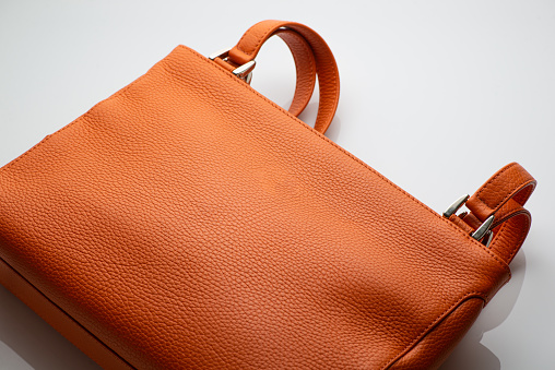 Close-up of a fashionable orange women's handbag on white background