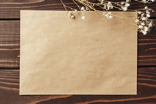 Blank sheet of paper with flower branch on wooden background flat lay