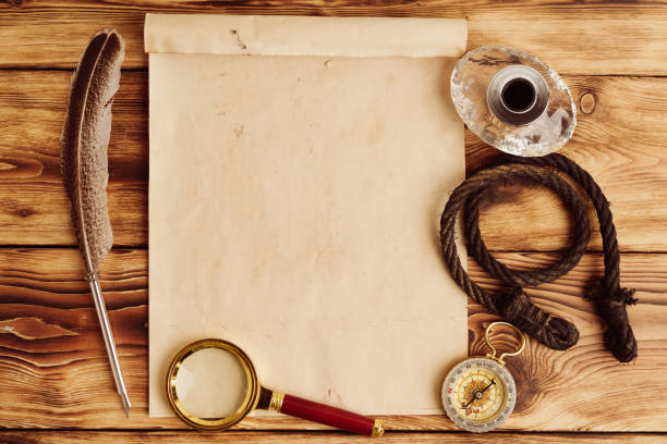 istock Old paper on brown wood background with feather 1558028614