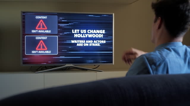 Man emotionally reacts on Hollywood Writers Actors Strike Warning on TV screen