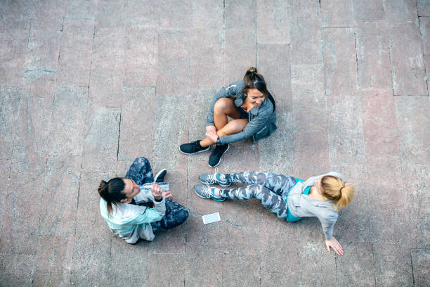 Women friends runners relaxing sitting on the floor after training stock photo