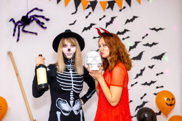 istock Young women in Halloween costumes. devil and skeleton 1558070721