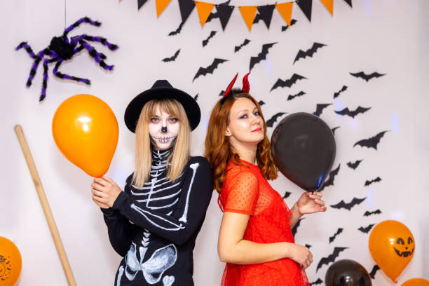 istock Two young women dressed as a devil and a skeleton have fun and pose for the camera on Halloween. 1558071262
