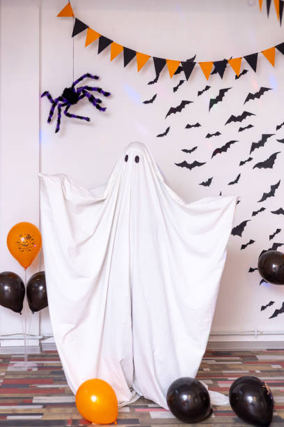 istock A man in a ghost costume from a sheet on a decorated background for the Halloween holiday. 1558072829