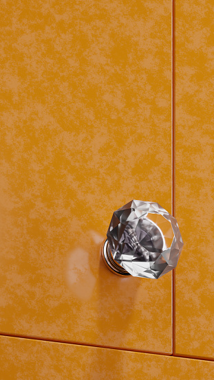 Crystal knob handle on orange cabinet front from three quarter front view