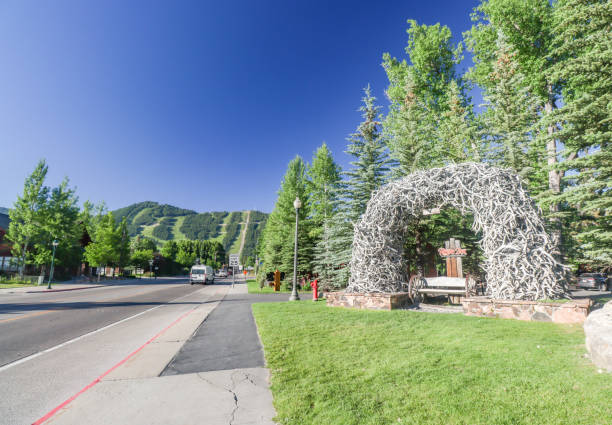 Traffic can be seen in the background of an Elk Antler Arch for The Rustic Inn Creekside Resort & Spa on North Cache Street at Jackson Hole in Teton County, Wyoming. This is a commercial venue.