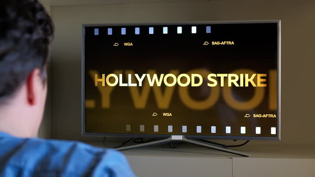Man emotionally reacts on Hollywood Strike Warning News on TV screen