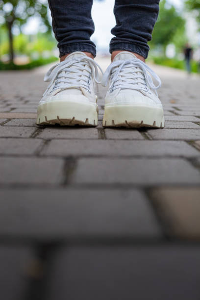 istock White sneakers with studded soles on female legs in black jeans 1558122995