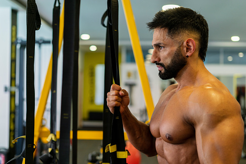 Latino man of average age of 35 years with a black beard dressed sportily is inside the gym training his body