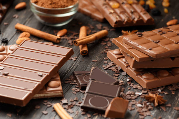tavolette di cioccolato al latte e caramelle su sfondo scuro. - brown chocolate candy bar close up foto e immagini stock