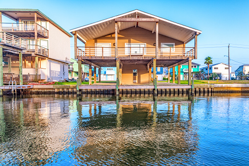 Galveston, United States - June 12, 2022:  Homes on stilts along a canal adjacent to the Gulf of Mexico on Galveston Island, Texas on an early summer afternoon.