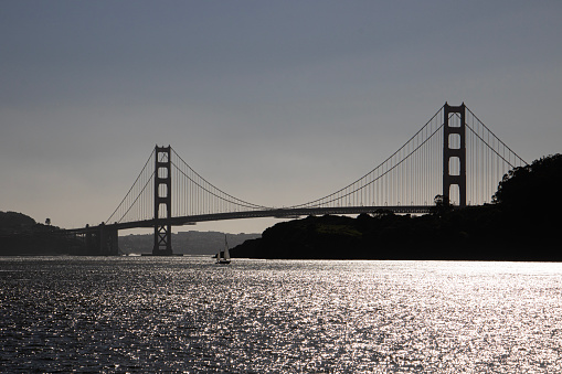 A silhouette shot of the Golden Gate bridge in the early evening sun, shot from the Sausalito side, on the sea.