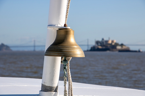 Close up shot of a ship's bell crossing from Sausalito to San Francisco bay with Alcatraz island and Oakland Bay Bridge in the background.