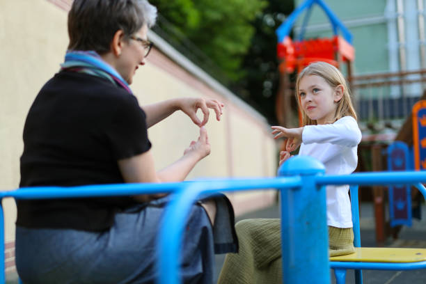 istock Sign language communication with a deaf child on a playground. 1558170573