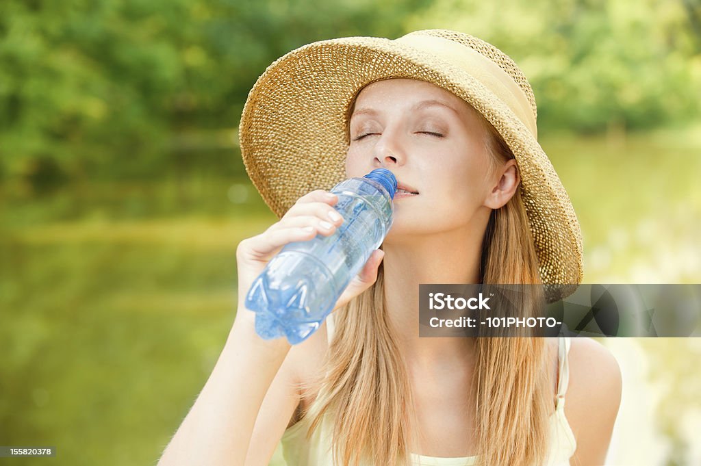 Girl in straw hat bebidas de agua - Foto de stock de Beber libre de derechos